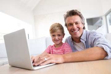 Smiling father and son using laptop in living room