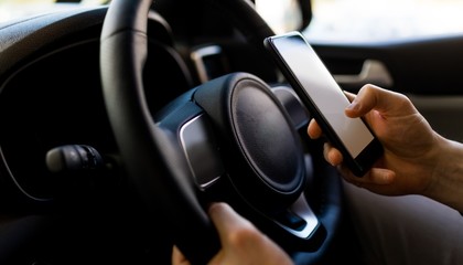 Naklejka premium Close-up of man using smartphone while test driving in car