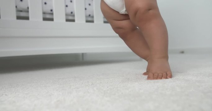 Baby Legs Standing and Learning Balance. a close up of baby feet and legs learning balance and moving feet around on carpet
