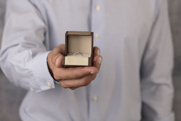 Engagement ring in man hands. Man holding jewellery close up. Love, Wedding, Proposing, Marriage concept.