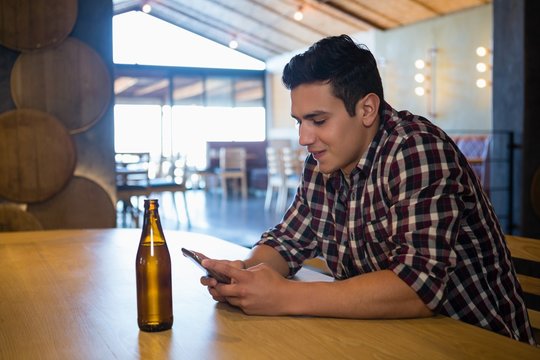 Man with beer bottle using phone