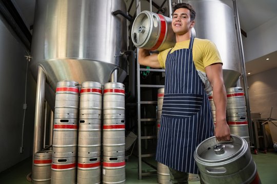 Portrait of man with kegs by storage tanks