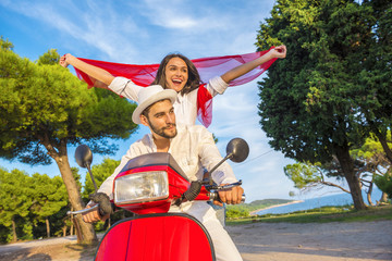 Happy free freedom couple driving scooter excited on summer holidays vacation.