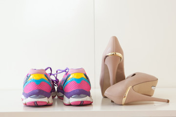 A pair of colorful sports shoes next to high heel stilettos.
