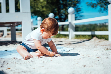 Little baby boy sitting on the sand