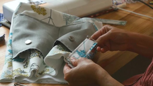 fashion designer adding fabric to handmade artistic bag in studio
