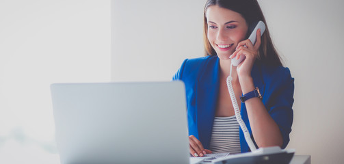Portrait of a young woman on phone in front of a laptop computer