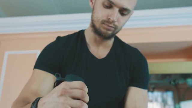 Buffed young caucasian bearded guy mixing milk in glass bowl using whisk at kitchen table, panoramic shot