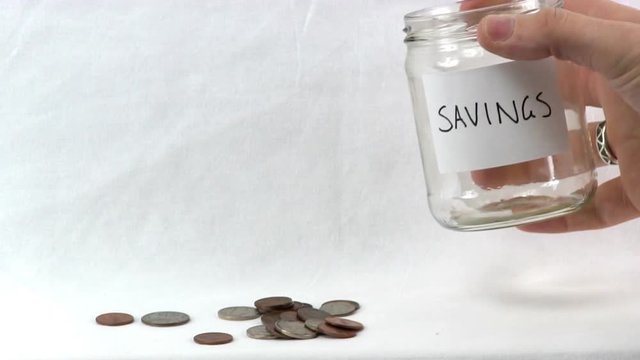 Coins emptied from clear medium sized glass jar labeled as savings