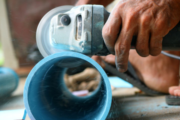 Asian workers use electric circular saw cutting the PVC pipe 