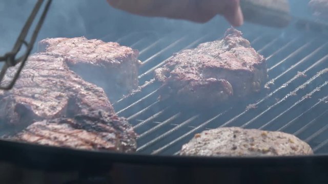Man's hands cooking steak on grill