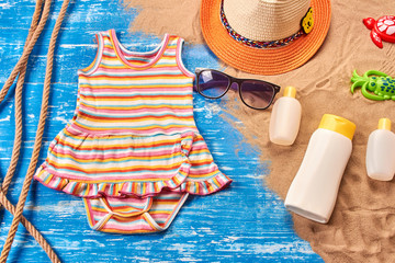 Baby Child summer stuff to the beach on a blue wooden background with rope and sand. Top view.