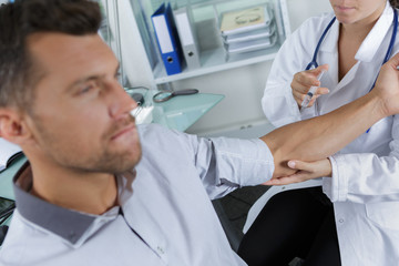 male doctor injecting a patients arm in the medical office