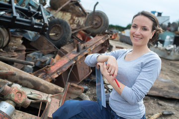 Fototapeta na wymiar woman working next to a rusted metal scrap pile