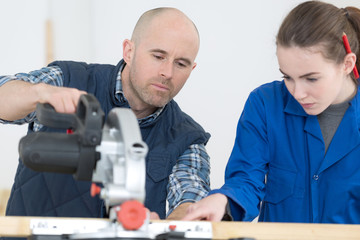 female apprentice using circular saw in carpentry workshop