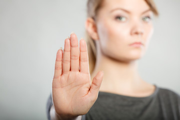 Female shows stop sign by her hand.