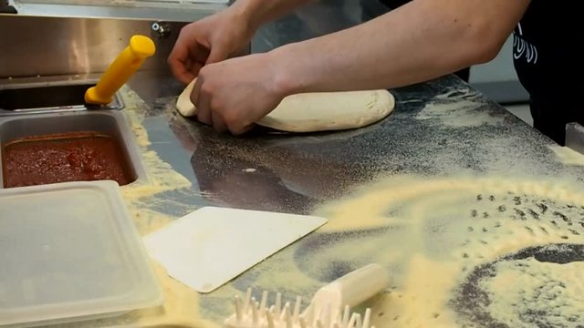 Chef prepares a pizza for catering. Warm-up and shaping of dough for pizza. Concoction of flour and making tortillas. 