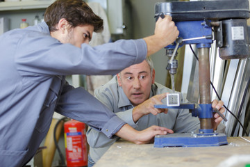 engineer teaching apprentice to use milling machine