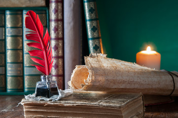 Quill pen, old papers and books by candle light
