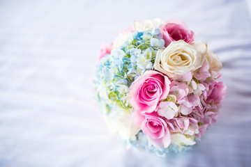 Beautiful bouquet of roses on the white bed.