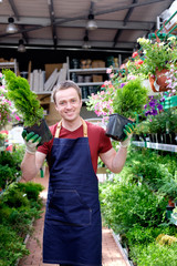 young man seller in plant market greenhouse at work