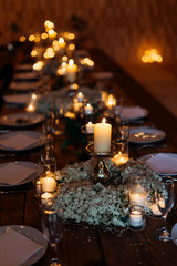 Table set for an event party or wedding reception with quiet atmosphere created by plenty of candles and forget-me-not flowers