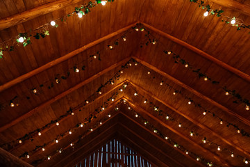 Wooden ceiling decorated with electric bulbs and green garlands