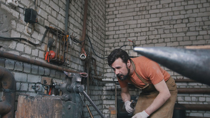 Muscular blacksmith in forge near metal anvil