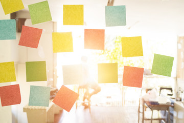 Empty sticky note on window in the office with vintage tone and sun light.