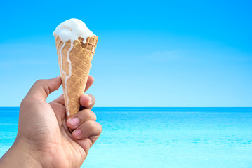 hand holding ice cream cone background the sea and blue sky.