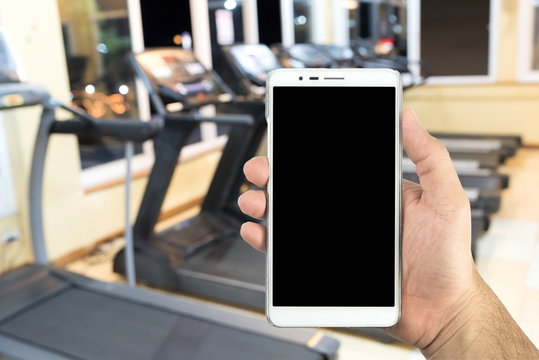 Man hand holding a smart phone in the fitness center.