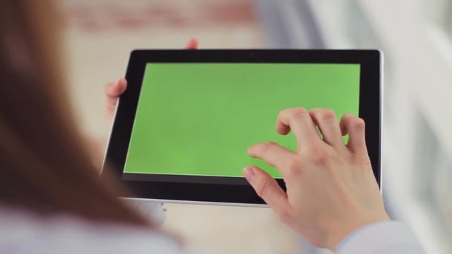 Female doctor hands with a tablet computer with green screen. Modern medicine.
