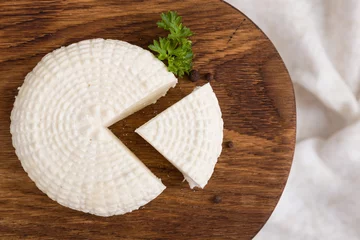 Deurstickers Zuivelproducten Bovenaanzicht op gesneden ronde witte zelfgemaakte kaas - traditioneel melk romig zuivelproduct op vintage houten bord. Rustieke stijl.
