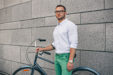 Fototapeta na wymiar Confident business man with bike. Confident young handsome man in shirt and glasses holding bicycle while standing against white background