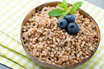 Buckwheat porridge in a bowl with mint leaves and blueberries.