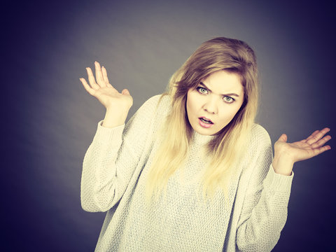 Confused young blonde woman gesturing with hands
