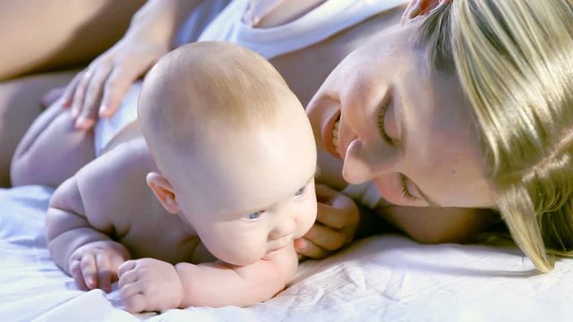 Happy mother and baby having fun on the bed