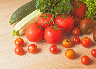 Tomatoes, parsley, zucchini and lettuce on a wooden table.