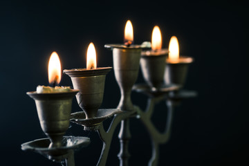 old handicraft candelabrum with burning candles against art dark background (selective focus, shallow dept of field)