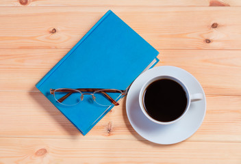 Book, glasses and coffee cup on  wooden background. Top view