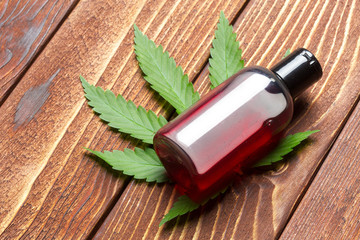 Cannabis leaves and oil on wooden background
