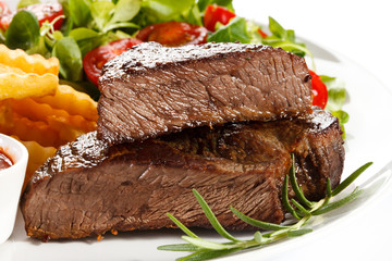Grilled steak, French fries and vegetables on white background 