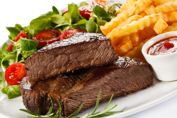 Grilled steak, French fries and vegetables on white background 