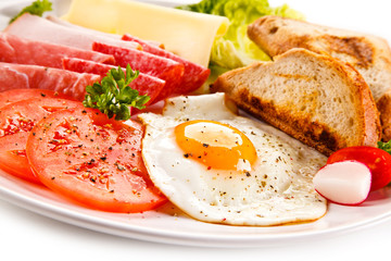 Breakfast - toasts, fried egg and sausages, cheese, ham and vegetables