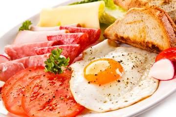 Breakfast - toasts, fried egg and sausages, cheese, ham and vegetables