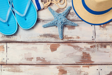 Summer vacation background with flip flops, starfish and hat on wooden board. View from above