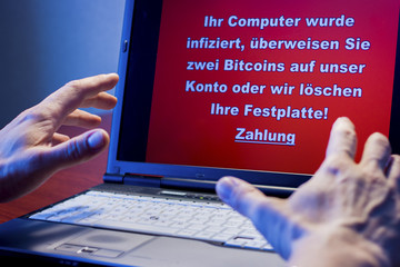Ein Computer der mit einem Virus infiziert wurde davor ein geschockter Benutzer