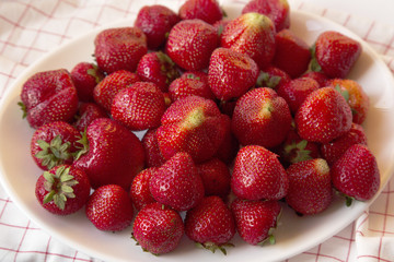 Fresh Ripe Red Strawberries on a White Plate with Crumpled Napkin. Close-up Horizontal Top View Picture.
