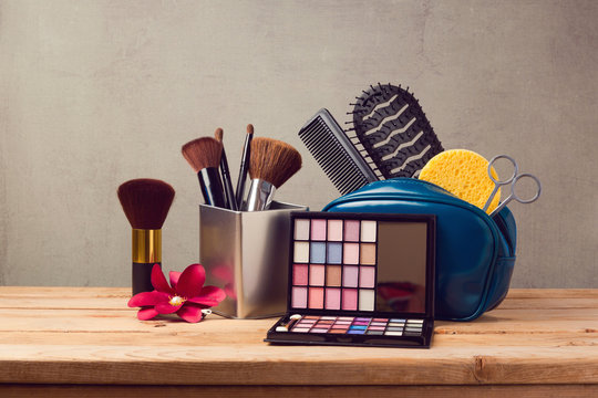 Makeup and beauty products on wooden table over gray background