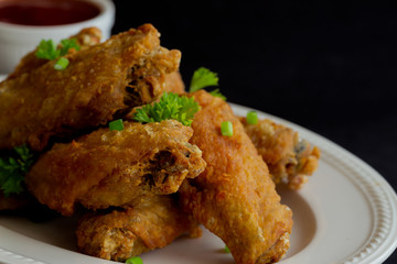 Fried chicken wings on white plate served with barbecue dipping sauce. Homemade fried chicken delicious and crispy. Close up fried chicken and chili sauce or tomato sauce (ketchup) ready to served